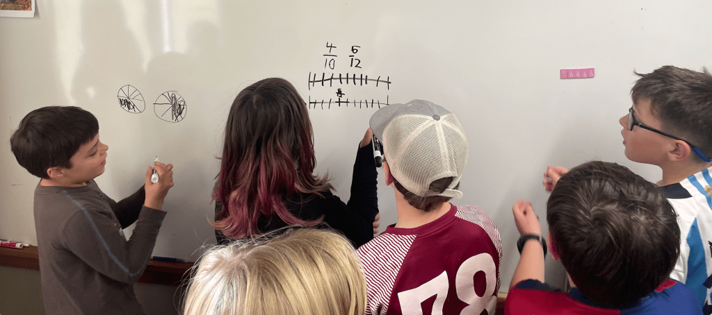Students at whiteboard looking at fractional representations.